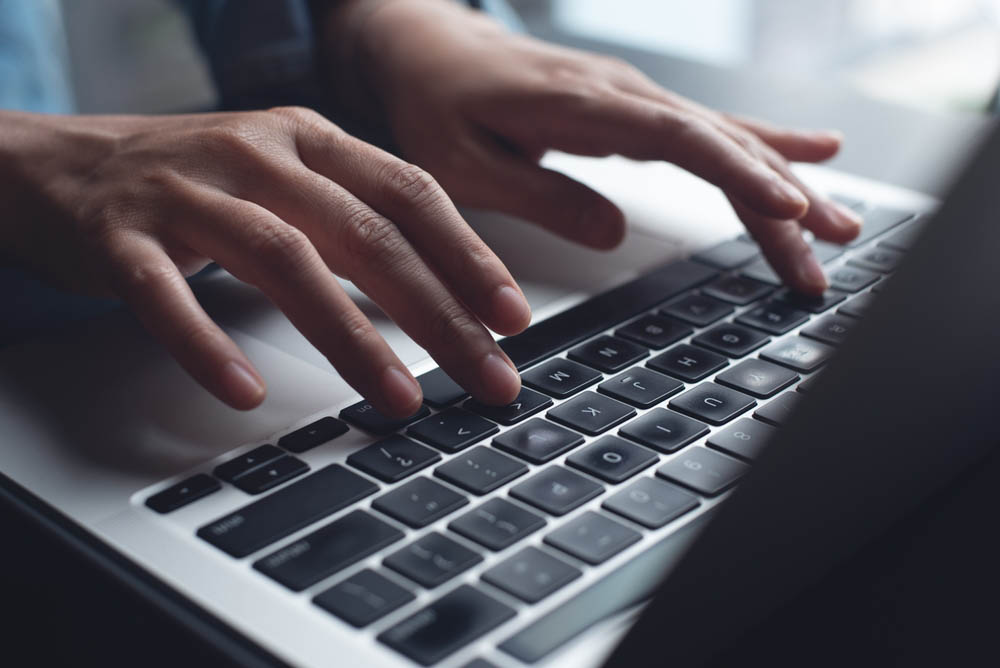 close-up of hands typing on a laptop