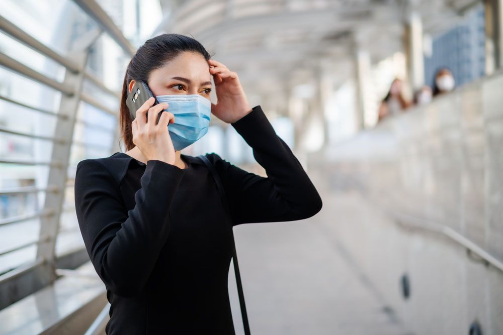 person in face mask using phone