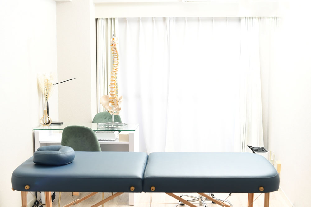 clinic room with chiropractic table, medical posters of the spine, and adjustment tools